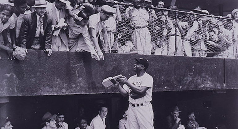 Jackie Robinson gives an autograph before a game