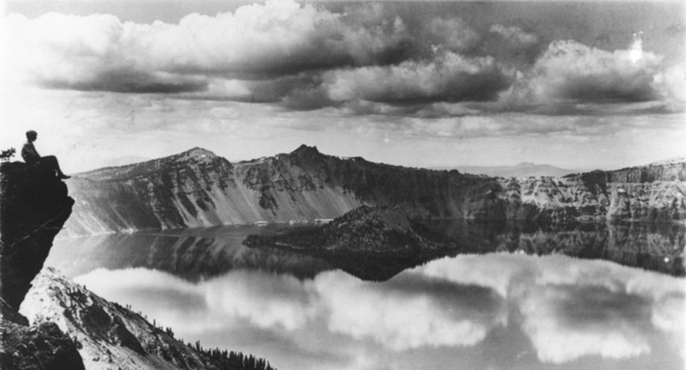 A tourist sits contemplatively at the edge of Crater Lake