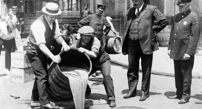 Prohibition agents pour liquor down a sewer