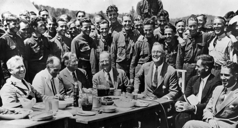 FDR sits with a group of CCC workers at a table at Big Meadows on Skyline Drive in Shenandoah National Park, Virginia