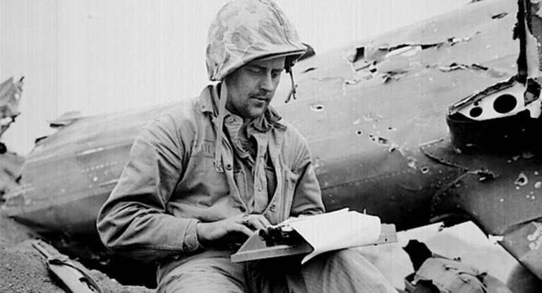 A United Press reporter makes his office atop a wrecked Japanese plane on Iwo Jima