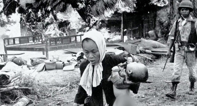 An older woman and child escape a burning village in Vietnam.