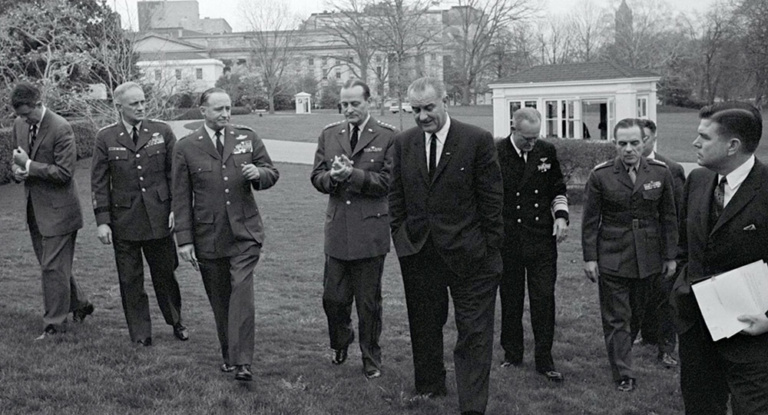 President Johnson stands on the White House lawn with military advisors.