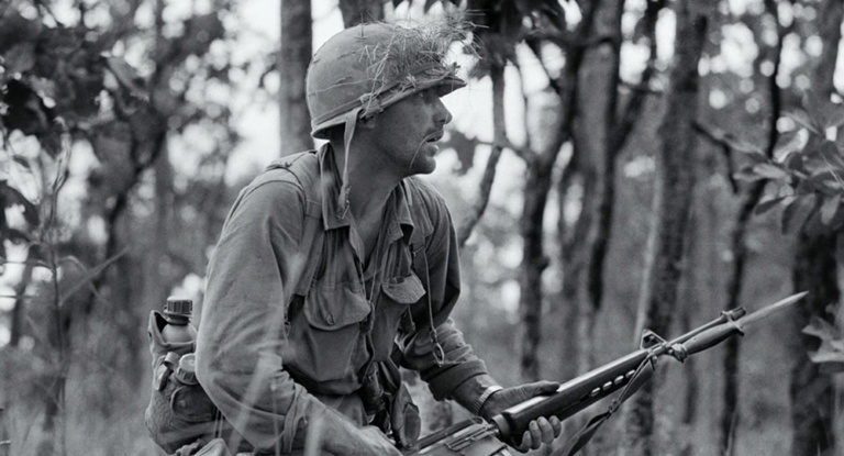 A soldier holds a gun with bayonet.